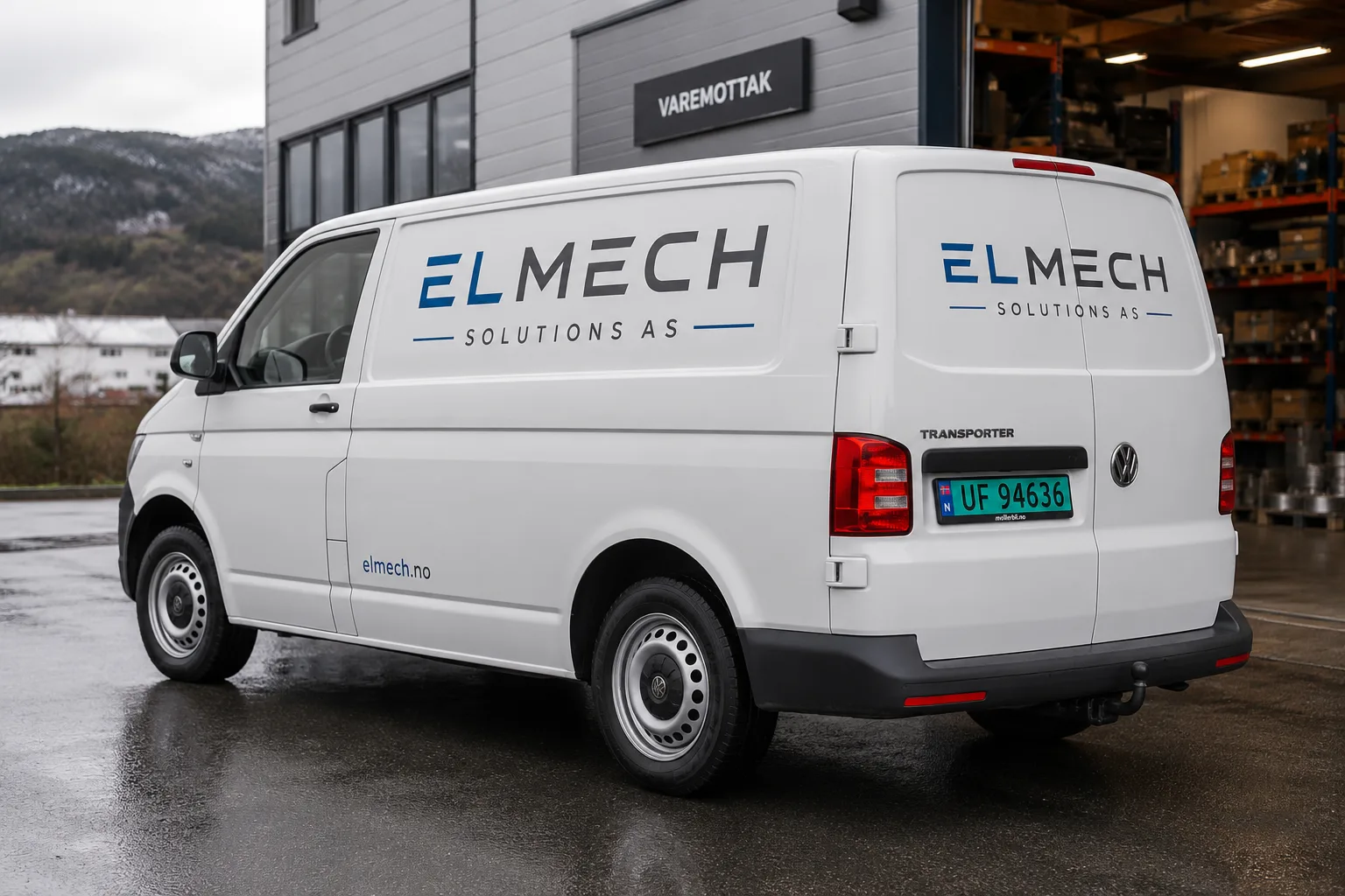 Kvit Volkswagen Transporter varebil med ELMECH-logo, parkert utanfor varemottak